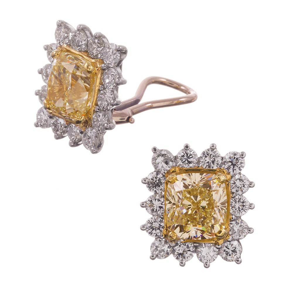 Attractive and timeless in every regard and an important and sophisticated addition to any attire, these classic cluster earrings will find themselves a hallmark of your fine jewelry collection. The center cushion fancy yellow diamonds weigh 3.02