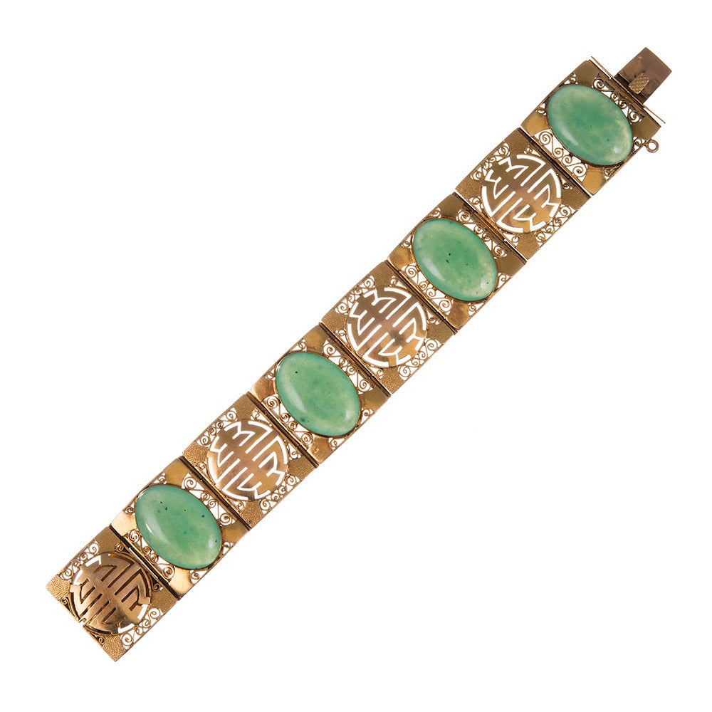 A lovely bracelet combining golden squares with intricate carvings with those set with large jade cabochons. 7 inches long and 1 inch wide. 18k yellow gold.