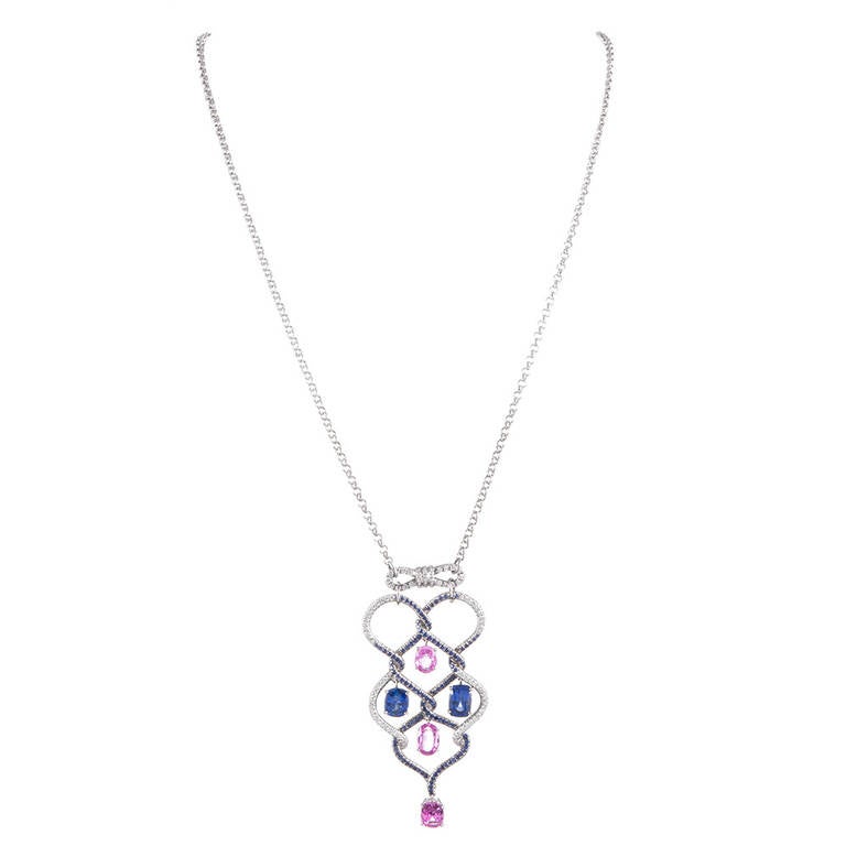 A super-feminine creation, celebrating movement, this necklace combines the undulating look of woven diamonds and blue sapphires, with trembling pink- and blu sapphires, which sit suspended within the frames. A small diamond bow at the top. The