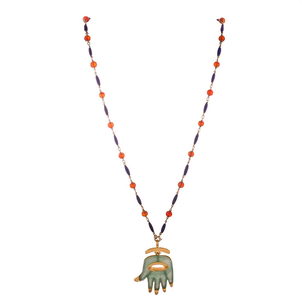 A chic means of warding off evil spirits, this Hamsa pendant is carved of green aventurine, set on 18k yellow gold and signed “A. Cipullo”, measuring 2 by 1.25 inches. It is suspended from a 25 inch antique chain combining carved carnelian beads