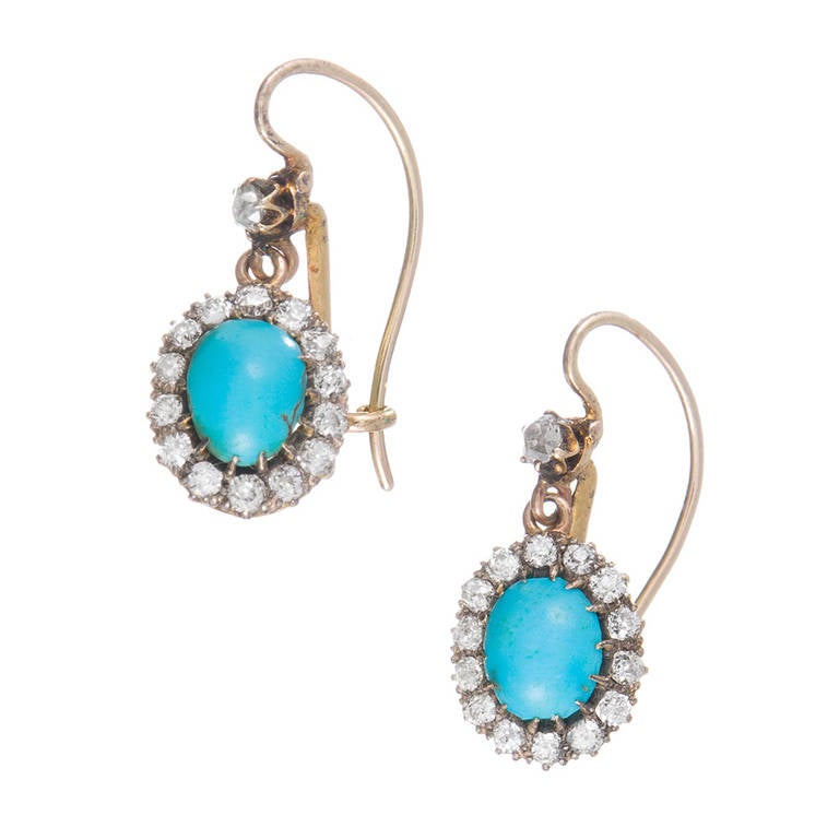 Yellow gold Victorian earrings comprised of a small diamond top and from it suspended a turquoise cabochon framed in diamonds. At just 3/4 inch long, these are the ideal earrings to add a pop of natural color to your daily wardrobe. We are offering