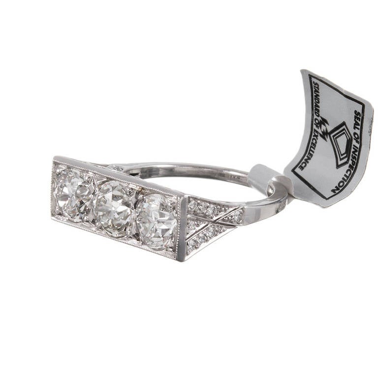A contemporary ring, the design inspired by classic art deco styles from the 1920s and 1930s, rendered in platinum, its square top set with three old European cut diamonds. This piece is a bit more substantial than an original art deco ring and