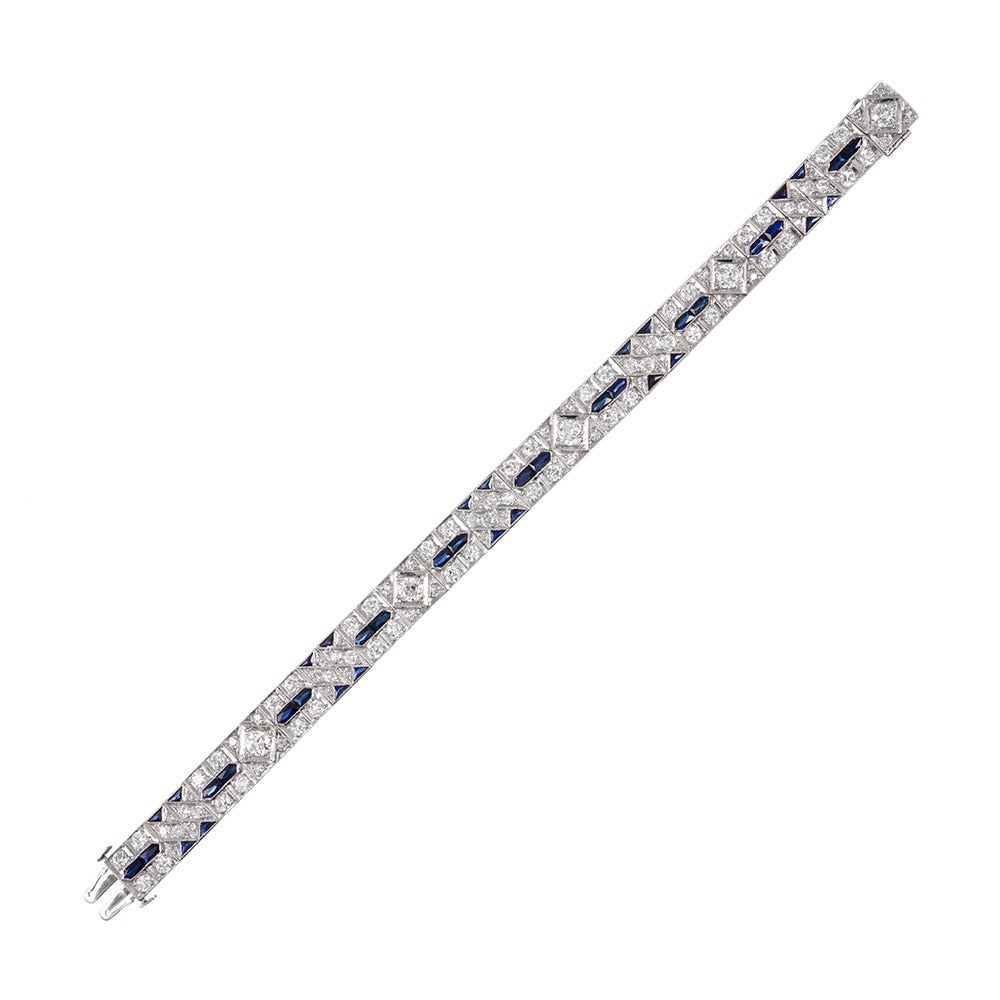 Iconic art deco styling, offering a symbiotic combination of geometrics in diamonds with sapphire accents. Rendered in platinum, with approximately 7 carats of brilliant white diamonds. 7 inches in overall length and 3/8 of an inch wide.