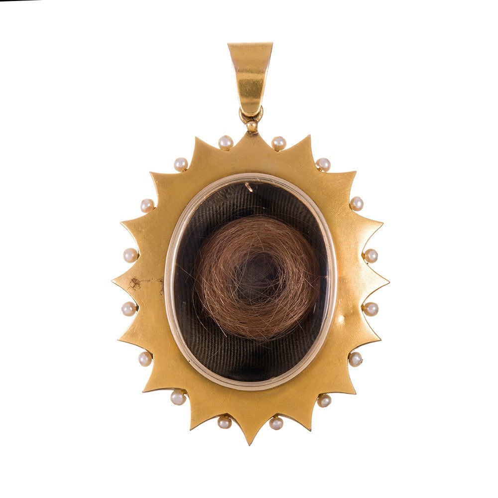 Substantial in size for a Victorian piece, this original yellow gold Victorian locket is designed as a sunburst of pattern created from a symbiotic combination of banded agate, pearls and black enamel. The original glass back is still intact, as is