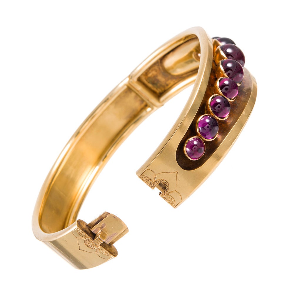 15k yellow gold oval bangle, a classic Victorian style that remains every bit as relevant for the fashion-conscious now as it was over a century ago. This one is decorated with a line of bezel-set cabochon garnets, graduated in size and exhibiting