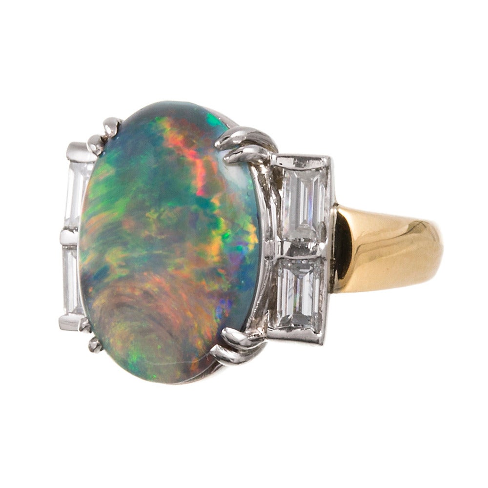 Rendered in 18k yellow gold with a platinum top, this is an unusual and beautiful ring with enough classical style elements to make it timeless, yet plenty of interest to keep it uniquely yours. The black opal center stone weighs approximately 5