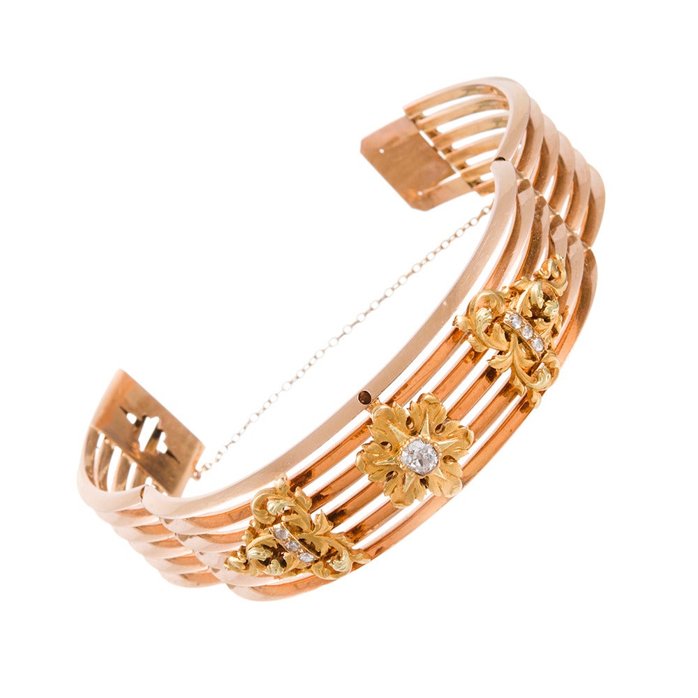 18k rose gold bangle, designed as a row of six triangular rows of gold and set with three gold motifs on the front. The centerpiece is decorated with a .60 carat old European cut diamond and flanking end pieces are set with rose cut diamonds. The