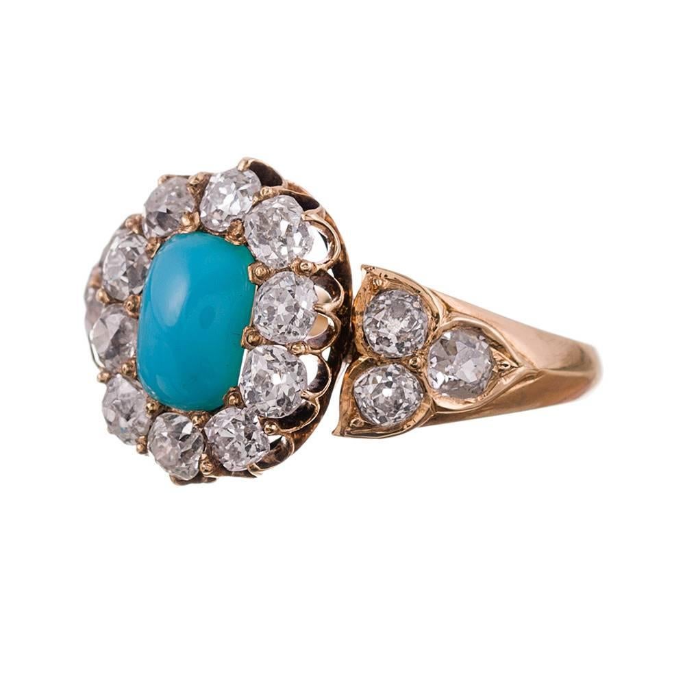18 karat yellow gold cluster ring set in the center with a turquoise
cabochon and framed with a crown of old European cut diamonds. A cluster
of three additional old European cut diamonds flanks the centerpiece. In
total, the diamonds weigh