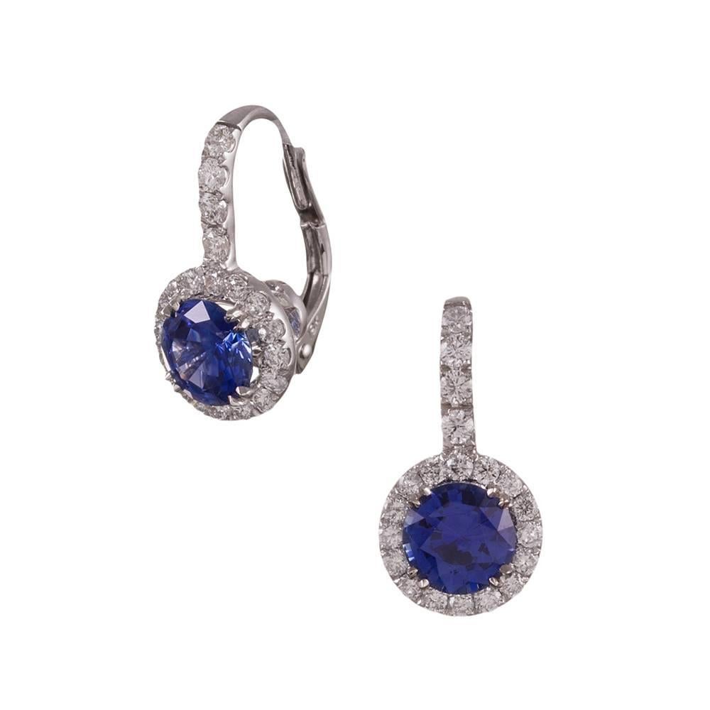 An ideally matched pair of round gem fine sapphires sit suspended from a frame of diamonds in 18k white gold. The sapphires weigh 2.48 carats combined, yet appear to be larger. In total, the diamonds weigh .75 carats. The combination of gemstones is