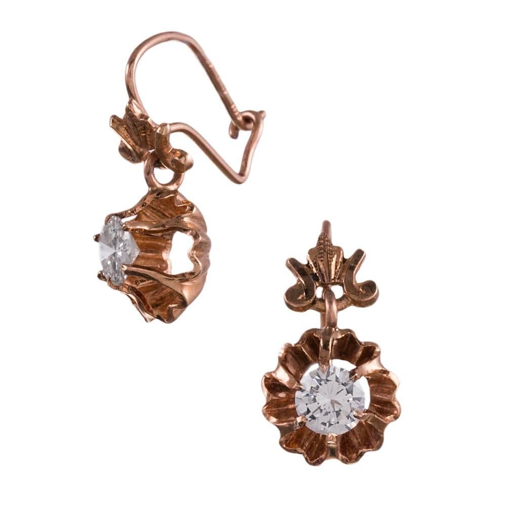 Sweet and charming earrings, made in America of 14k rose gold circa 1900. They display a belcher set diamond suspended from an architectural finial. The bottom moves gently, allowing the diamonds to catch the light. These adorable beauties measure