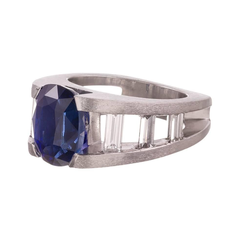 A modern sapphire ring, substantial both in design and weight, rendered in platinum and set with a 5.06 carat ruby center stone. There are 1.20 carats of white baguette diamonds forming a “ladder” up the shoulders. The bold structure protects the