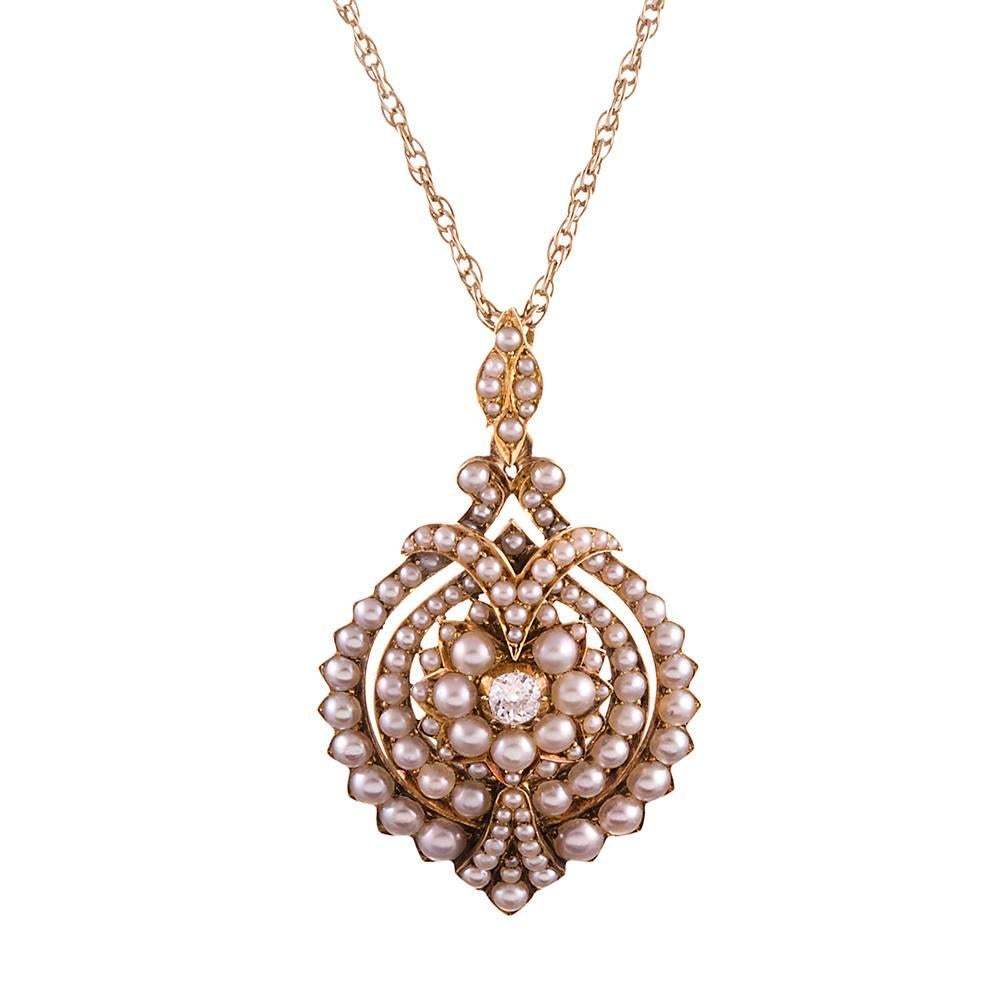 A feminine creation with an inspired design. Made of 18k yellow gold with rows of lustrous pearls framing a single old European cut diamond. The diamond weighs .50 carats. 2 inches tall including the bale and 1.25 inches wide, this is a lovely piece