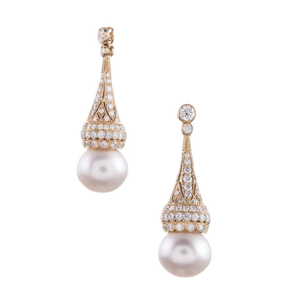 Three dimensional diamond-studded tops cap a pair of lustrous pearls, swinging gently from your ears. Pearls are the ultimate feminine accessory and, mixed with diamonds, the allure is augmented. In total, there are 2.60 carats of round brilliant