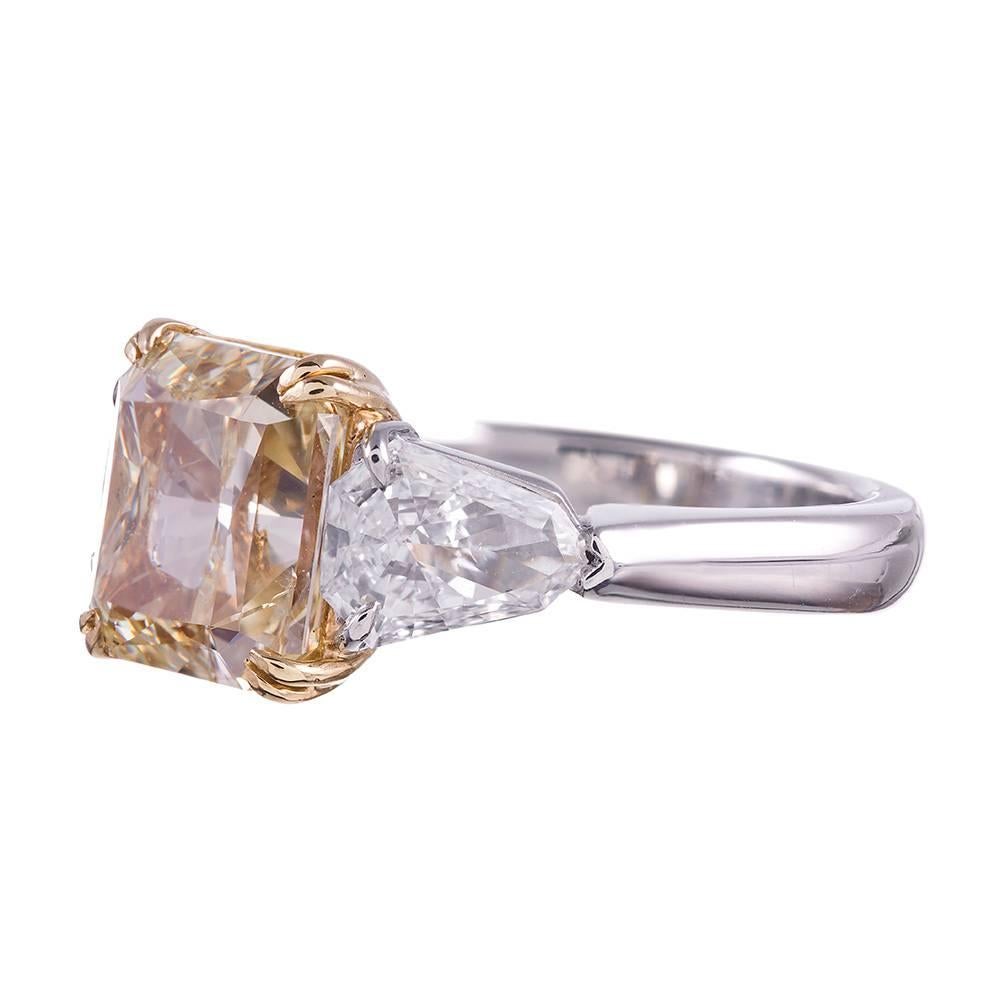 Classic, with a twist. The center diamond, a 5.02 radiant cut described by GIA as “Fancy Yellow” color with Si2 clarity, is flanked by a a pair of white shield shaped diamonds that weigh 1.80 carats in total. Set in platinum with an 18k yellow gold