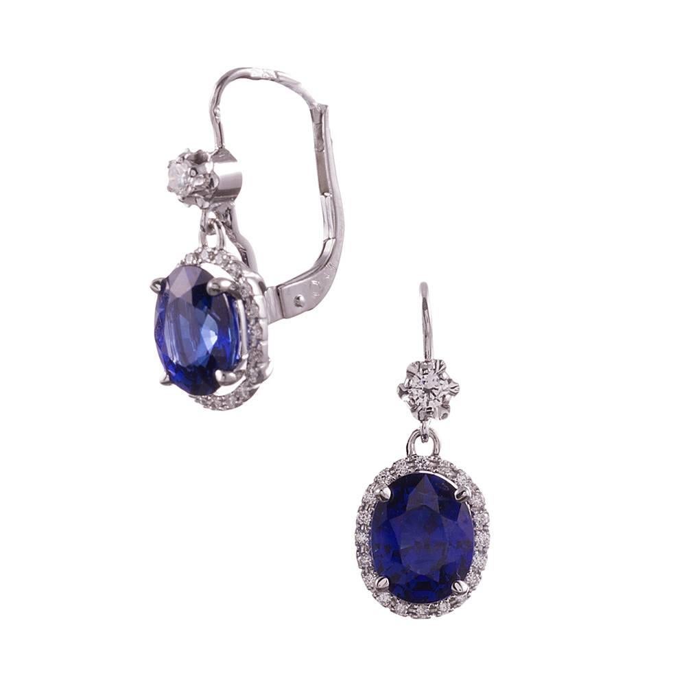 A lovely pair of earrings that are certain to collect compliments. Made of 18k white gold and set in the center with a faceted oval blue sapphire, then framed by a halo of diamonds. The sapphires weigh 3.50 carats in total and exhibit intense deep