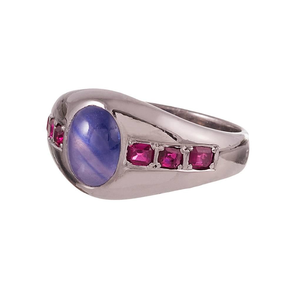 An 18 karat white gold gypsy ring set in the center with a 2 carat sapphire cabochon and flanked by three rubies on each side. The rubies weigh .60 carats in total. Red, white and blue equals a subtle nod to Americana. This ring is suitable for a