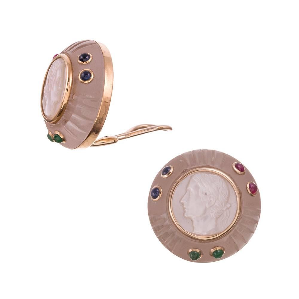 Carved buttons of rock crystal are set in the center with a profile portrait of mother of pearl and dotted with pairs of ruby and emerald cabochons. Polished bezels of 14 karat yellow gold surround each element. Trianon is the sister company to