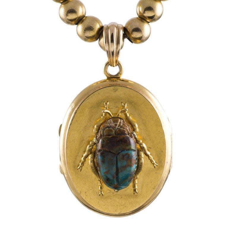 A 14k yellow gold locket which has been decorated with a turquoise scarab beetle. The locket measures 2 inches from top of the bale to the bottom, and 1 inch across.

*Pictured with yellow gold bead chain but sold separately. 