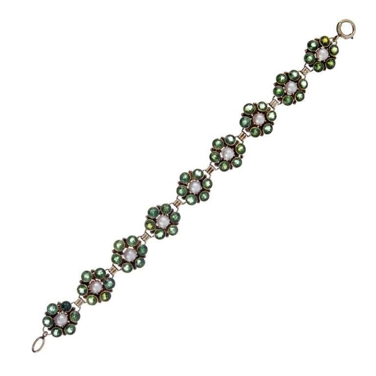Most likely 1960s or earlier, 14k yellow gold, designed as a row of nine clusters of bezel-set green tourmaline with a pearl at the center. Playful vintage style with the omnipresent 1960s flower theme. 7.25 inches.