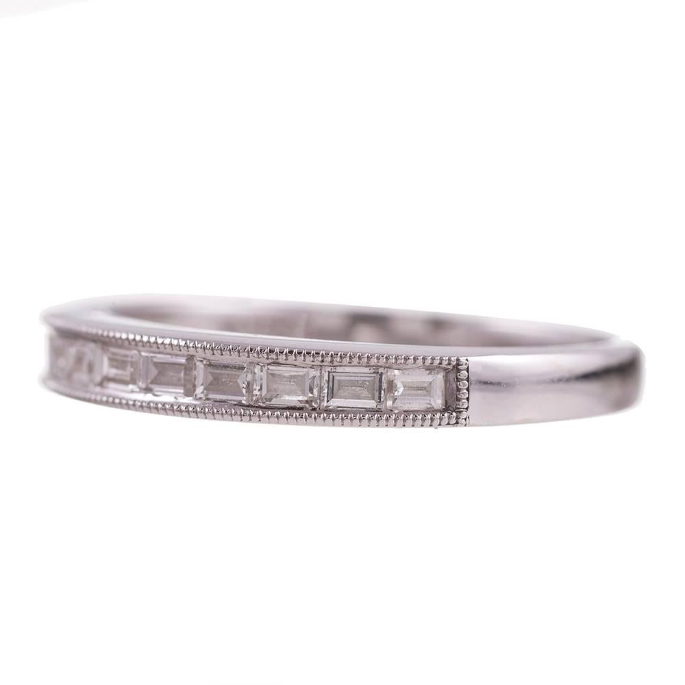 Channel set baguette diamonds, .75 carats in total, grace this half eternity band renderd in 18k white gold. Mille grain edges add a layer of feminine detail. This ring is a size 7.5 and can be resized on request.