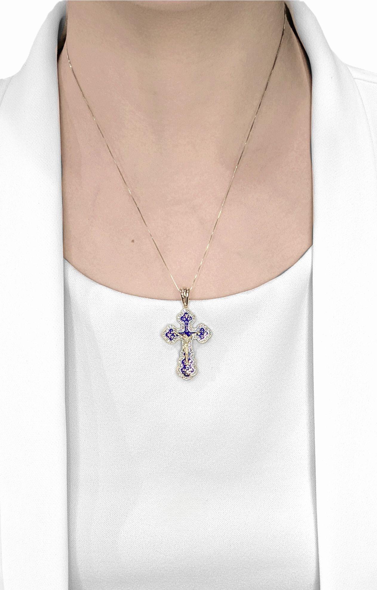 Embrassez la foi avec un art sophistiqué grâce à ce pendentif en forme de croix ornée, méticuleusement réalisé en riche or jaune 14 carats. Cette pièce remarquable présente une base en émail bleu vibrant, détaillée de manière complexe avec une