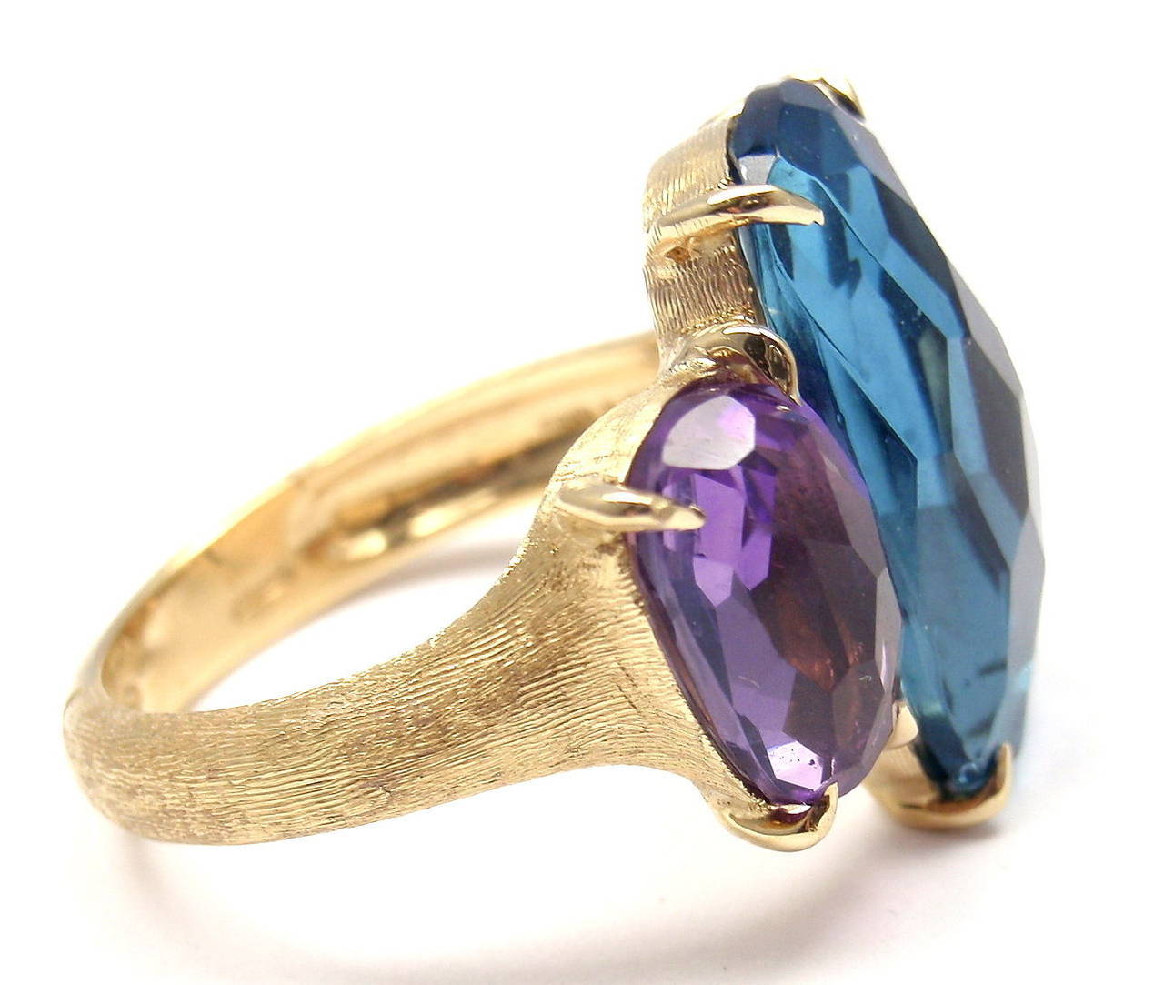 18k Yellow Gold London Blue Topaz Amethyst Murano Ring by Marco Bicego. 
With 1 London Blue Topaz 17mm x 10mm
1 Amethyst 10mm x 6mm

Details:
Ring Size: 6 (resizing is available)
Weight: 8.1 grams
Width:  17mm
Stamped Hallmarks: Marco Bicego