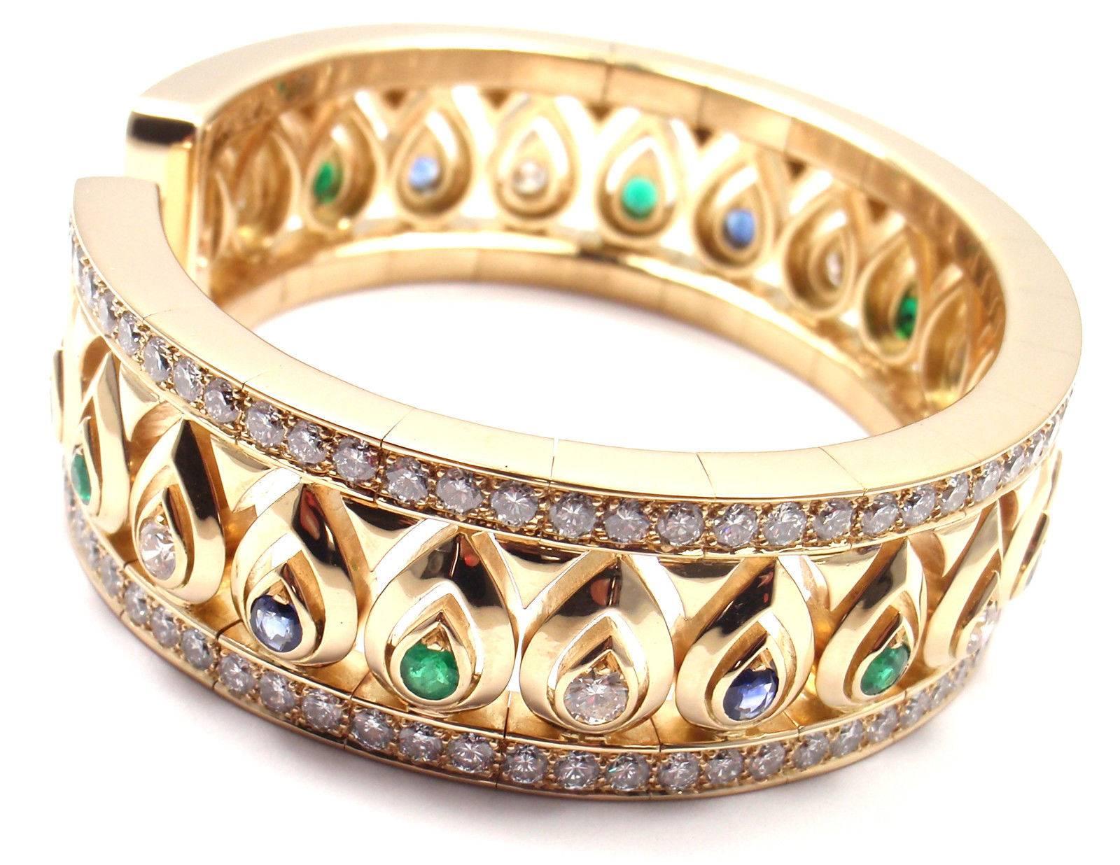 18k Yellow Gold Diamond Sapphire Emerald Cuff Bangle Bracelet by Cartier. 
 With 151 round brilliant cut diamonds VVS1 clarity, E color total weight approx. 7.70ct
8 round sapphires 4mm each
7 round emeralds 4mm each
 
 Details:
 Length: 7