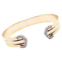 Bracelet manchette Cartier en or tricolore 18 carats, orné de diamants et du motif « Double C »