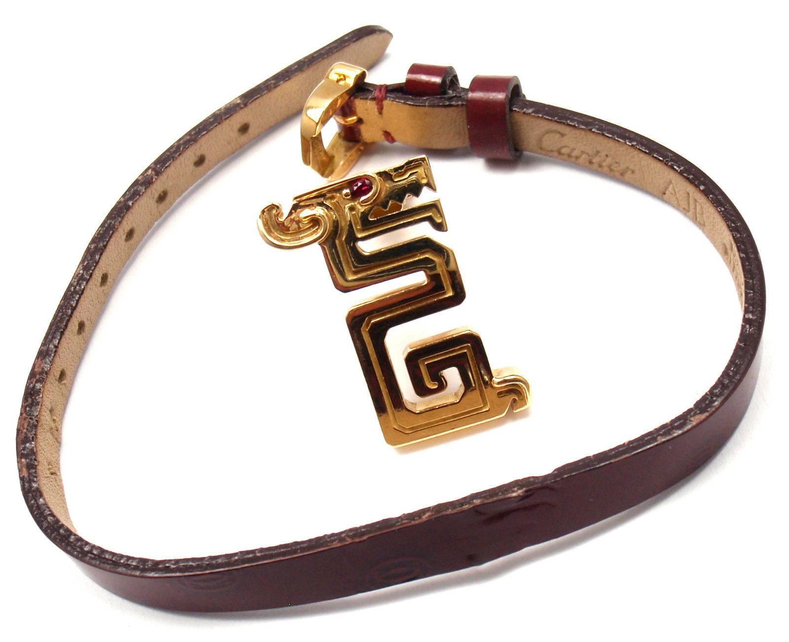 18k Yellow Gold Le Baiser Du Dragon Ruby Charm on a leather bracelet by Cartier. 
With 1 round cabochon ruby stone.

Details: 
Measurements:
Length Bracelet: 7.5