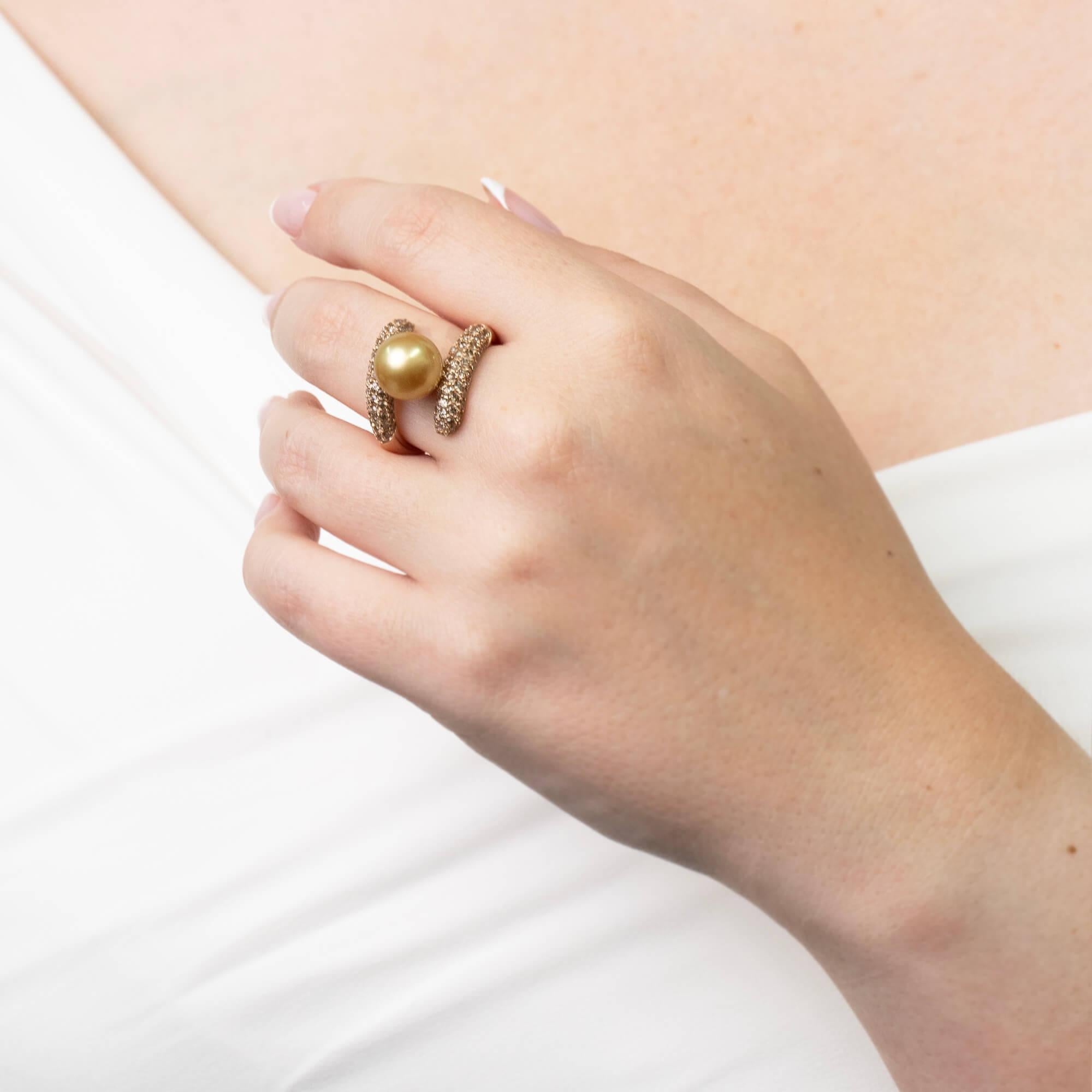 Ein Autore-Designerring mit einer goldenen Südseeperle und champagnerfarbenen Diamanten in Pflastertechnik auf einem abgerundeten Band aus Roségold. Gestempelt mit der 750er-Punze und dem Autore-Herstellerkennzeichen.

Edelstein: Eine goldene