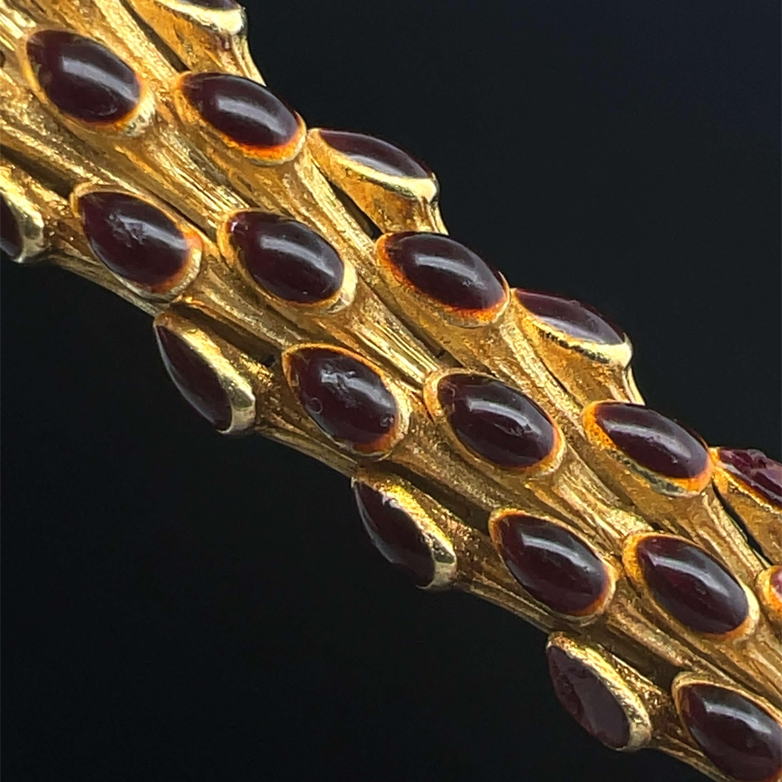 Esta pulsera de mediados del siglo XX del diseñador Tiffany & Co. está hecha en oro amarillo de 18 quilates y presenta piezas orgánicas articuladas de oro con puntas en forma de pera esmaltadas en rojo oscuro. Algunos dirían que representa escamas