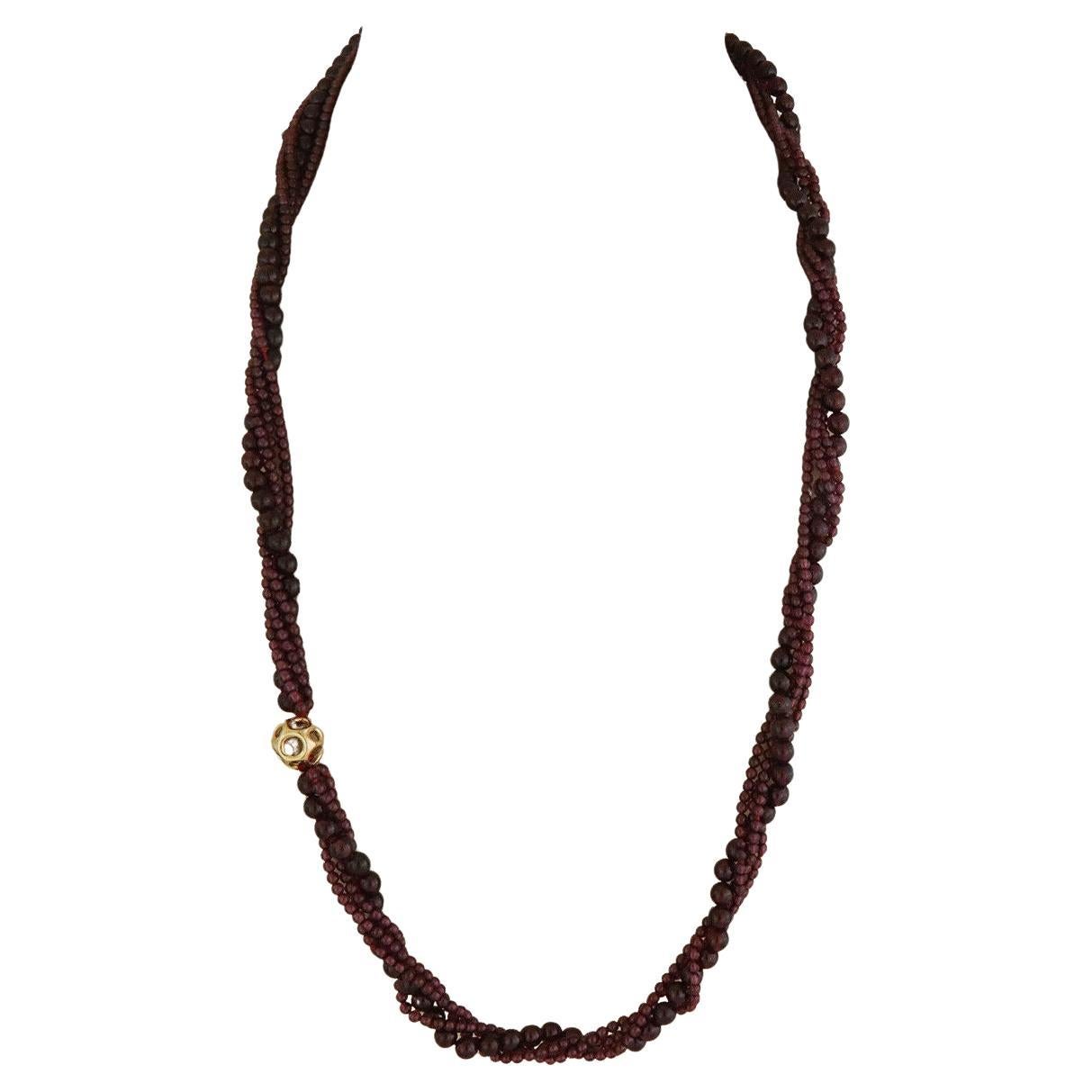 From Tiffany & Co. by designer Angela Cummings, this long elegant necklace has 4 strands garnet beads, 3 strands small beads, the 4th strand has larger beads. It is accented with a 13mm open style gold ball and it secure with a ring and hook clasp