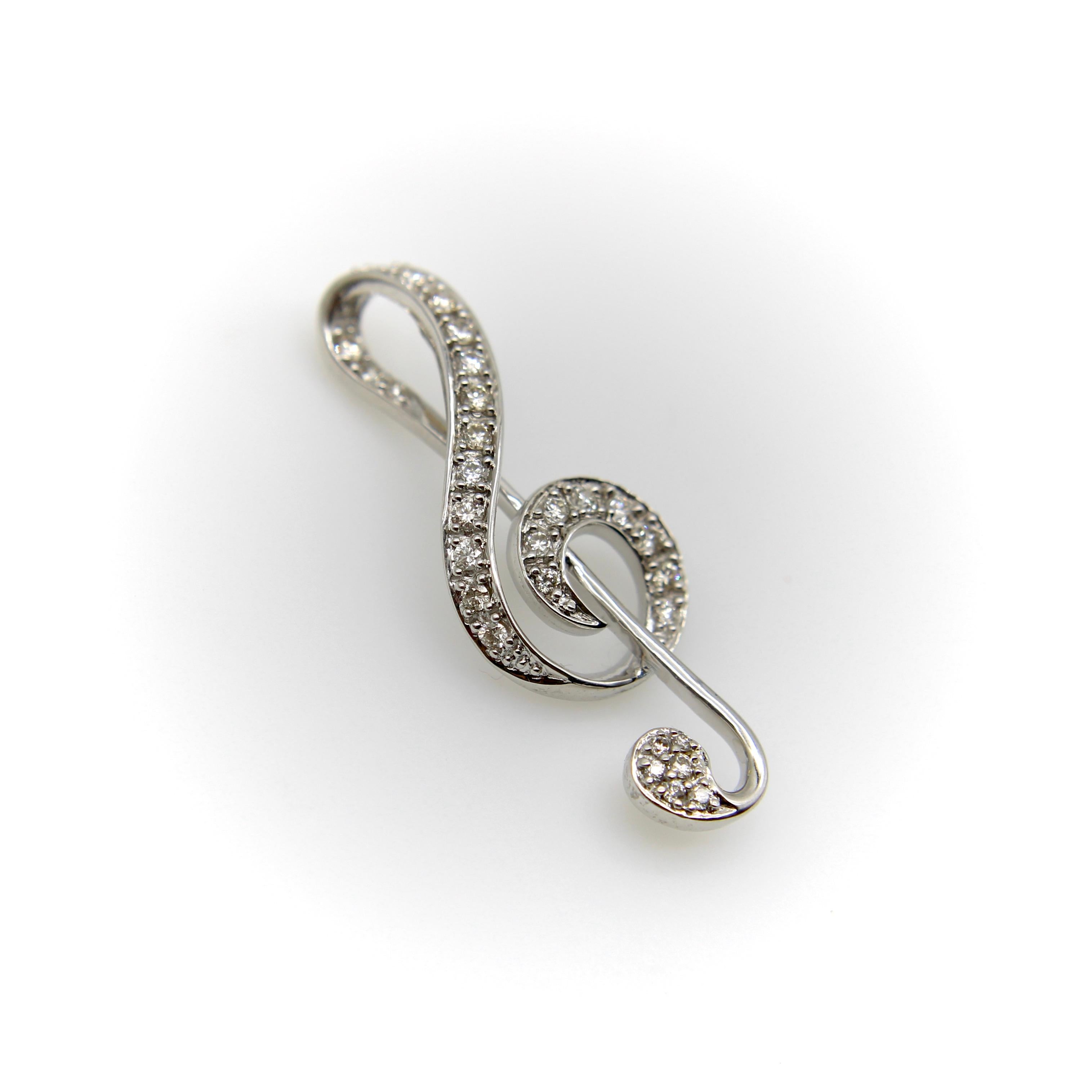 Signe musical important et symbole emblématique des mélomanes, cette clé de sol en or blanc 18k brille de diamants incrustés. Les courbes plongeantes en font un bijou élégant, et l'anse est construite dans la forme de la clé de sol, de sorte qu'elle