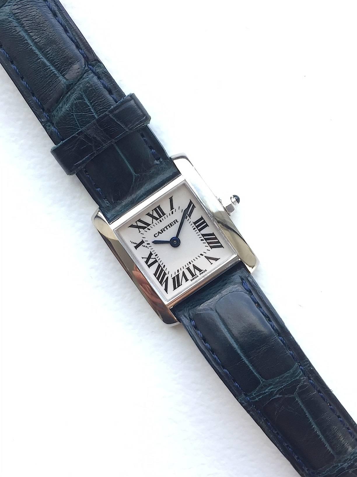 Cartier 18K White Gold Ladies Tank Quartz Watch
Classic Cartier Tank Design with Roman Numeral Markers 
White Colored Dial with Cartier Blue Hands 
22mm x 22mm Case 
Cartier Cabochon Crown 
Sapphire Crystal 
Quartz Movement 
Comes Fitted on A