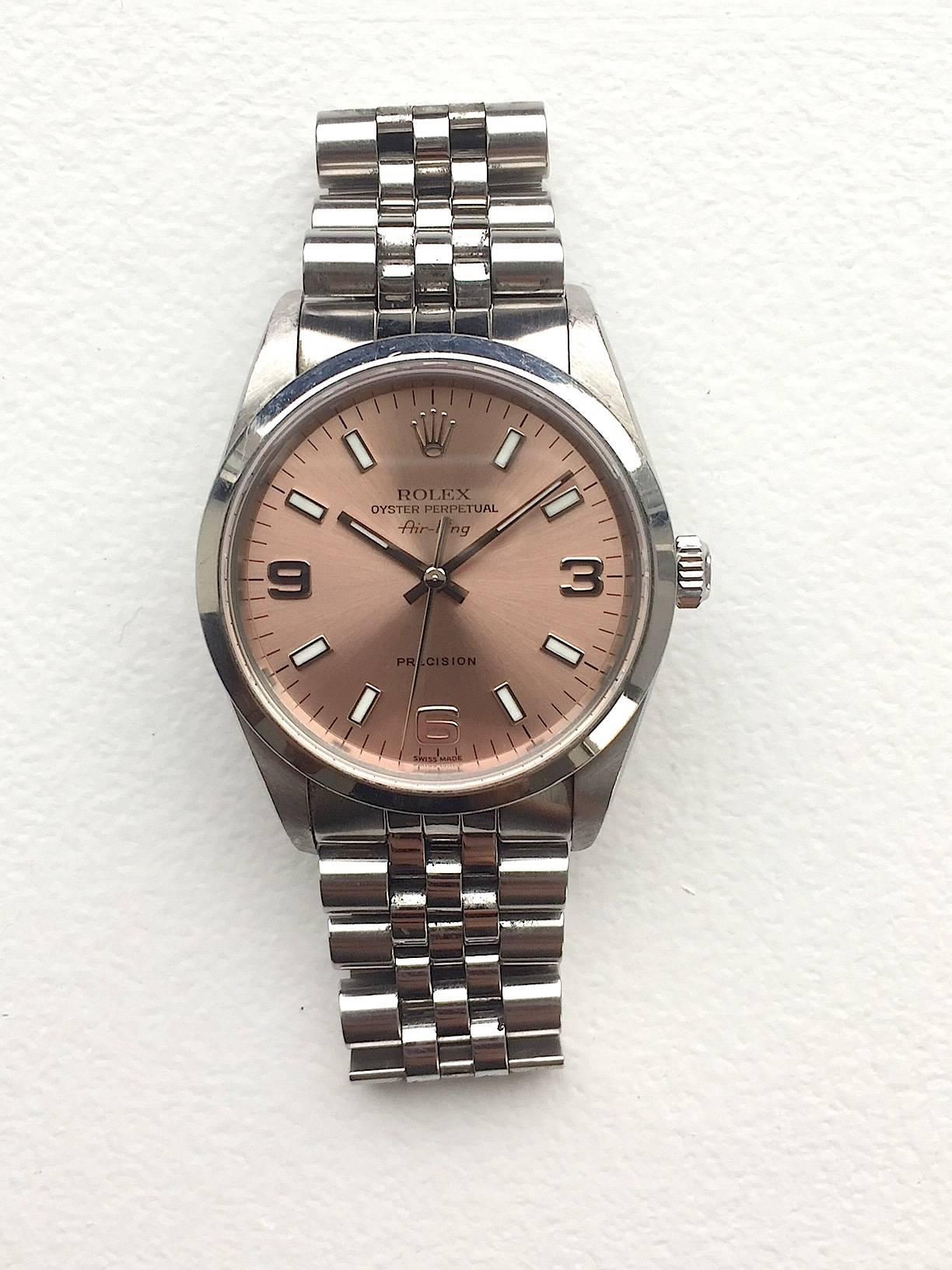 Rolex Stainless Steel Oyster Perpetual Air-King Precision Wristwatch
Factory Pink/Salmon Colored Dial with 3,6,9 Arabic Hour Markers
Smooth Stainless Steel Bezel
Stainless Steel Case
34mm in size 
Features Rolex Automatic Movement 
Sapphire