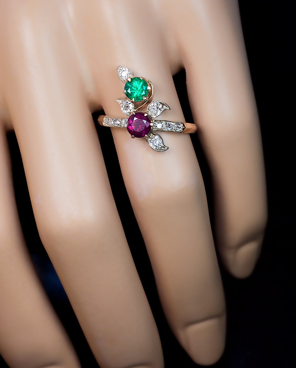 Made in St. Petersburg between 1904 and 1908

The 14K rose gold ring is designed as a stylized flower in Art Nouveau taste.
The ring is set with a round faceted emerald (approximately 0.37 ct), a round faceted ruby (approximately 0.60 ct), and