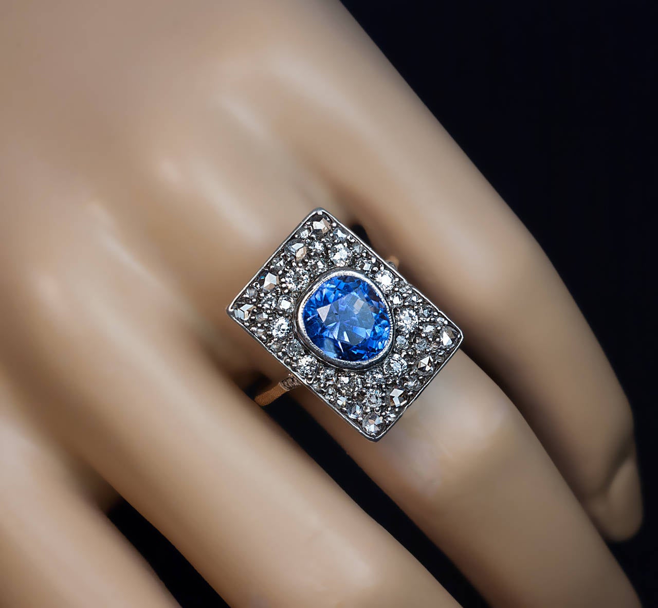 Silver topped 18K gold ring centered with an egg-shaped faceted natural unheated blue sapphire of an excellent even color, estimated weight of the sapphire - at least 5 carats, the sapphire surrounded by old European, cushion and rose cut diamonds,