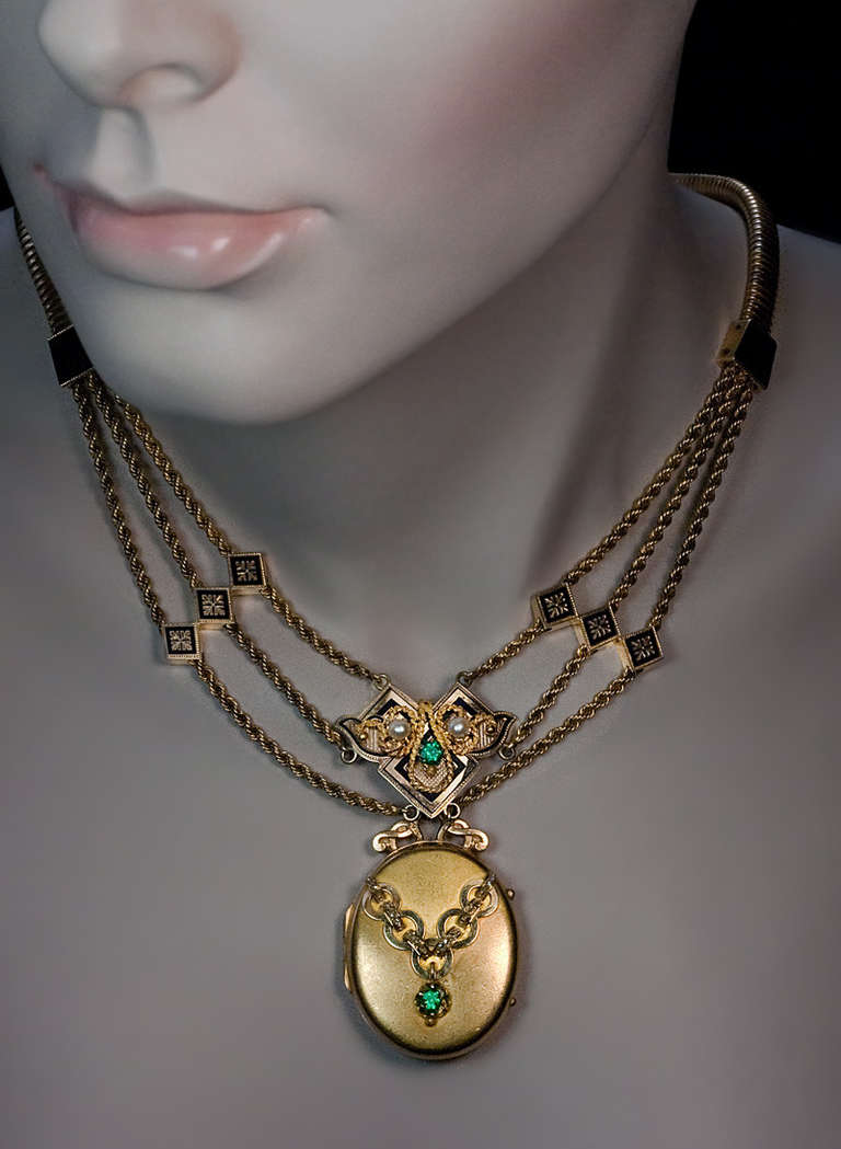 Made in Moscow in 1871 by Adler & Co.

A 14K gold necklace with detachable locket is embelished with black enamel, two emeralds, two half pearls and rose cut diamonds. 

 Length 44 cm (17 1/4 in.)

Total weight 56.11 grams