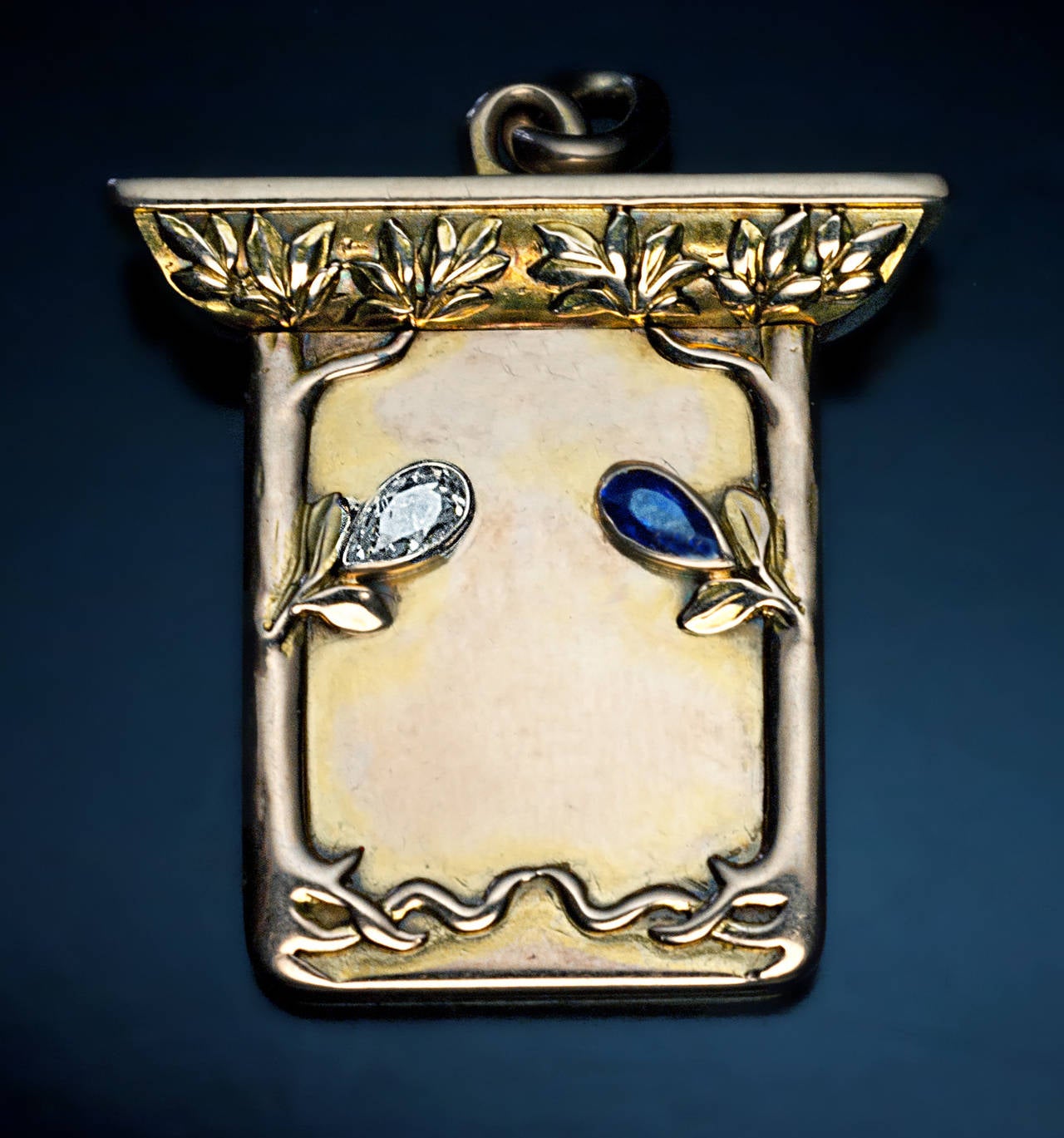 Made in Moscow between 1899 and 1908 by W.A.Bolin, jeweler of the Russian Imperial Court

The front of the locket is decorated with two stylized trees in Art Nouveau taste, embellished with a pear shaped diamond and a blue sapphire. The interior