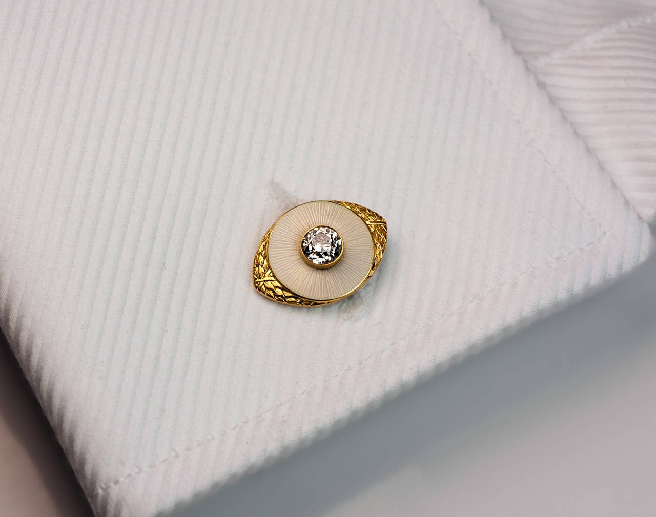 A pair of 14K gold, pearl white guilloche enamel and diamond cufflinks by Joseph Marshak

Made in Kiev between 1908 and 1917

The guilloche enamel discs are centered with two old European cut diamonds (approximately 0.70 ct tw) and flanked by