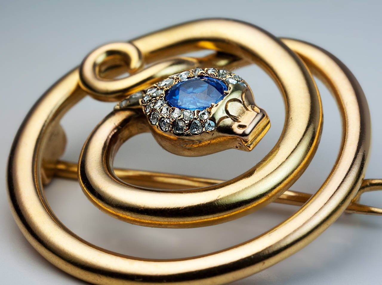 A Stylish Antique Victorian Era Snake Brooch Pin

made in St. Petersburg between 1882 and 1898

The 14K gold brooch is designed as a stylized coiled snake.
The head of the snake is embellished with a blue sapphire (approximately 0.42 ct)