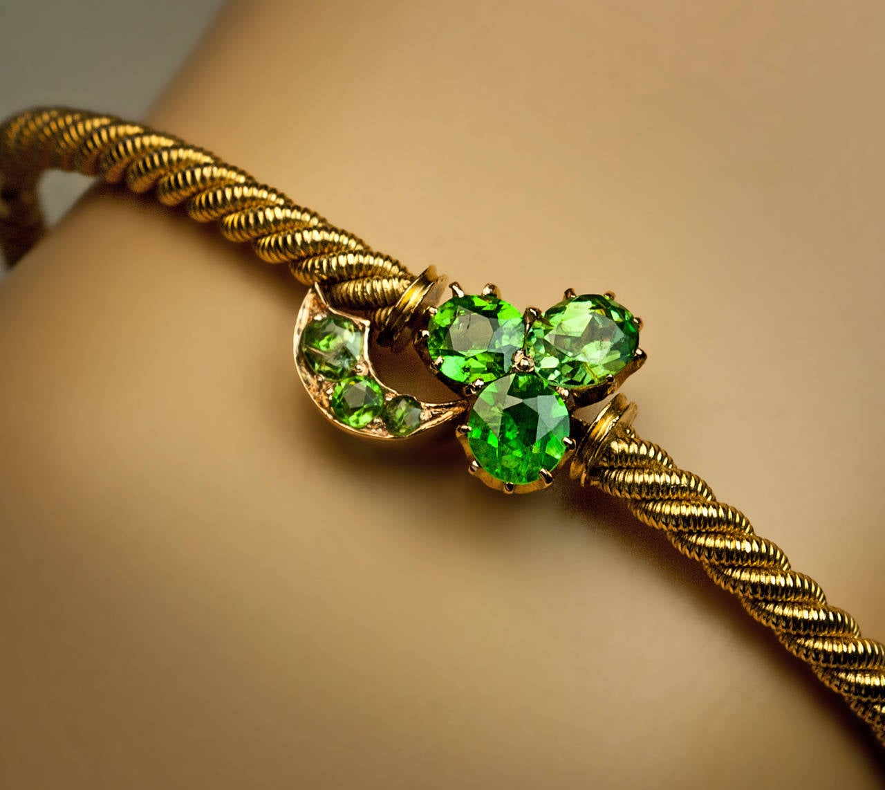 14K gold swirl bangle bracelet centered with a stylized clover set with sparkling vivid green Russian demantoids, made in Saratov (Russia) between 1882 and 1898, marked with 56 zolotnik gold standard and maker's initials

inner circumference 17.5