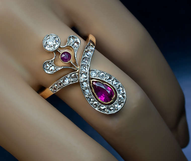 circa 1910

 A platinum topped 18K gold milgrain ring is set with a pear cut natural ruby (6.4 x 4 x 2.5 ct, approximately 0.46 ct), a small round ruby, an old European cut diamond (approximately 0.25 ct) and 26 rose cut diamonds.

Height 26 mm