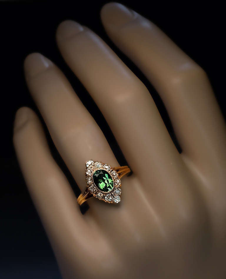 A Russian marquise shaped ring: bezel-set with an oval 1.61 ct demantoid garnet of exceptional brilliance surrounded by old cut diamonds.
The demantoid is unusually clean (most stones of this size will be heavily included) and full of fire. 
At