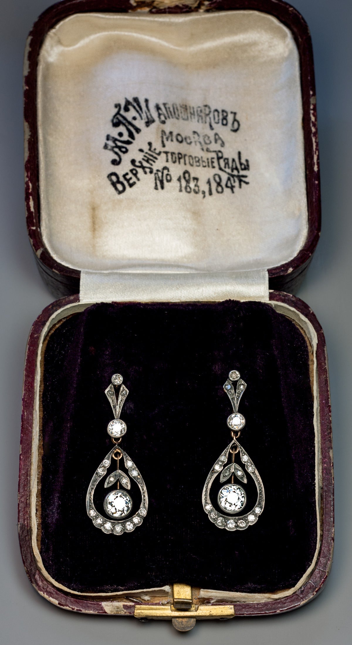 Made in Moscow between 1908 and 1917

The silver topped 14K gold earrings feature two bright white and sparkling old cut diamonds. 

Approximately 0.87 ct and 0.93 ct

They hang inside drop shaped frames embellished with diamonds.

Estimated