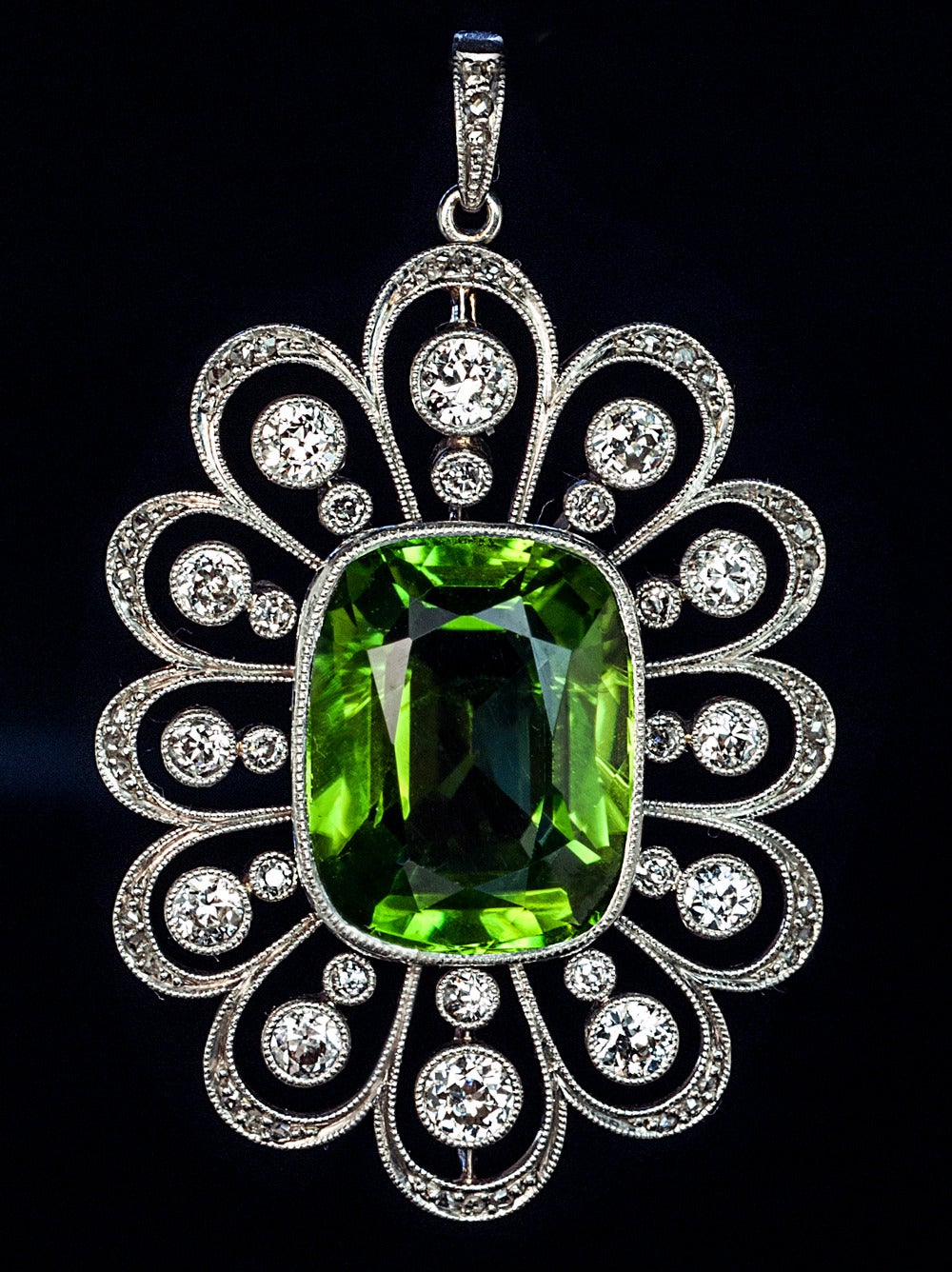 St. Petersburg, circa 1930

The pendant is designed as an openwork flower head, crafted in platinum and 14K gold, centered with a large cushion cut sparkling lime green peridot, called chrysolite (golden stone) in Russia.

Peridots / chrysolites