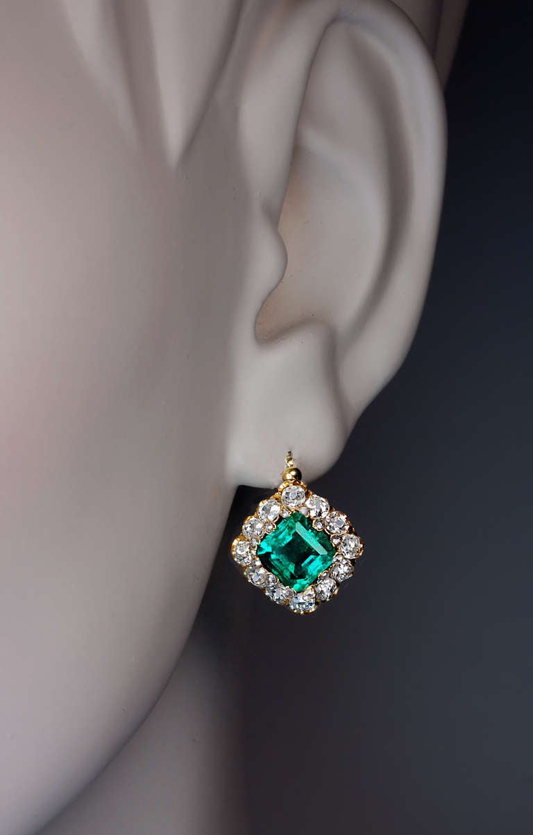 A pair of 18K gold French earrings, c. 1890, set with two emeralds: approximately 1.66 ct and 1.67 ct of excellent color and strong saturation ( vstbG 6/4 and vstbG 5/4).  The emeralds are surrounded by 24 rose cut diamonds and 24 old mine diamonds