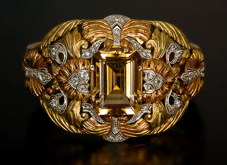 A unique Art Nouveau bangle bracelet of an openwork floral design, centered with a prong-set emerald cut citrin (approximately 19 carats) framed by superbly chased orange-yellow and green 18K gold foliage with diamond-set platinum