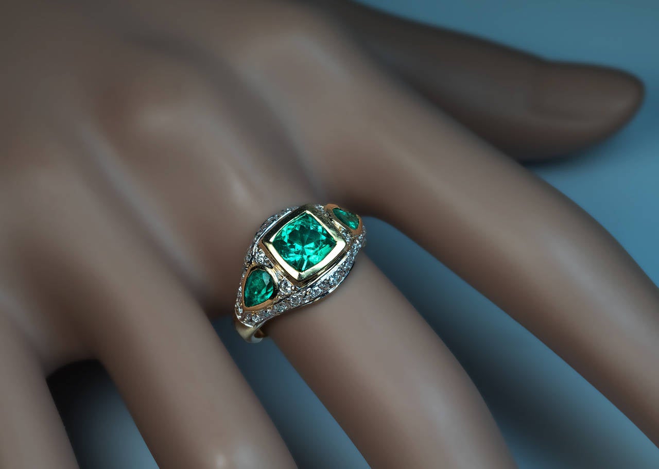 mid 1900s 18K gold ring bezel-set with three emeralds surrounded by numerous single cut diamonds, the center emerald approximately 1.20 ct and of an excellent color

marked with owl-shaped French import mark

ring size 6 1/2