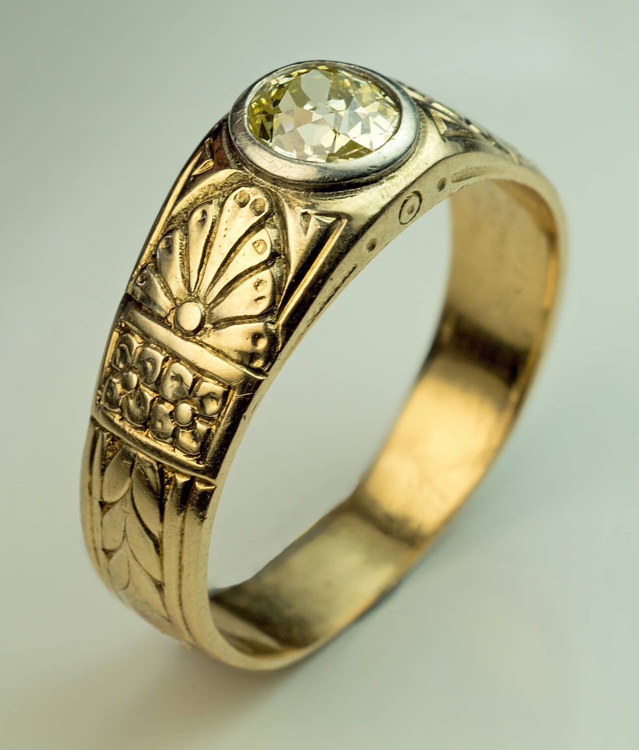 A Russian c. 1900 chased greenish-yellow 14k gold ring centered with an old cut fancy light greenish-yellow diamond (approximately 0.92 ct, VS1 clarity) set in a silver bezel

band width 8 mm (5/16 in.)

size 10.75